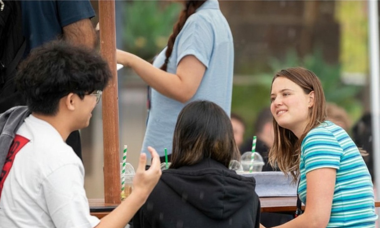 3 people sitting around a table in conversation.