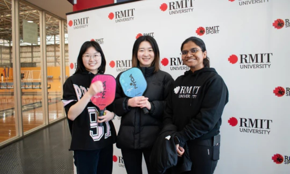 Three people holding rackets smiling