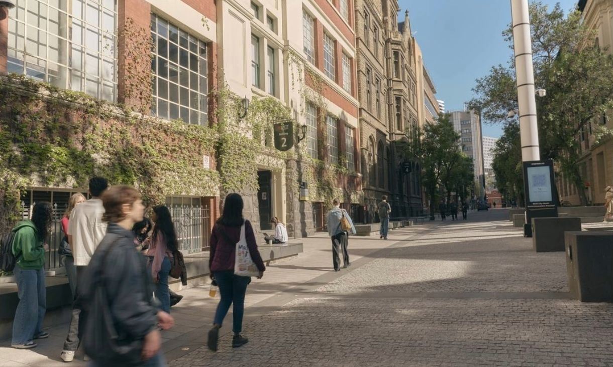 Students walking along Bowen Street past ivy-covered Building 2 on RMIT’s City campus.