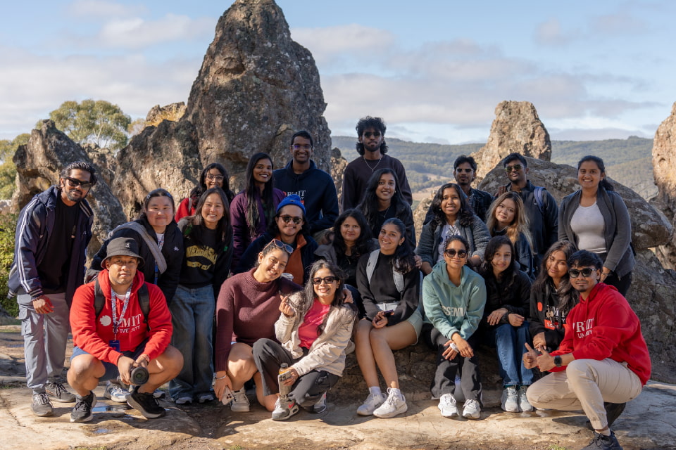 A group of students posing in front of a sign that reads 'Melbourne'.