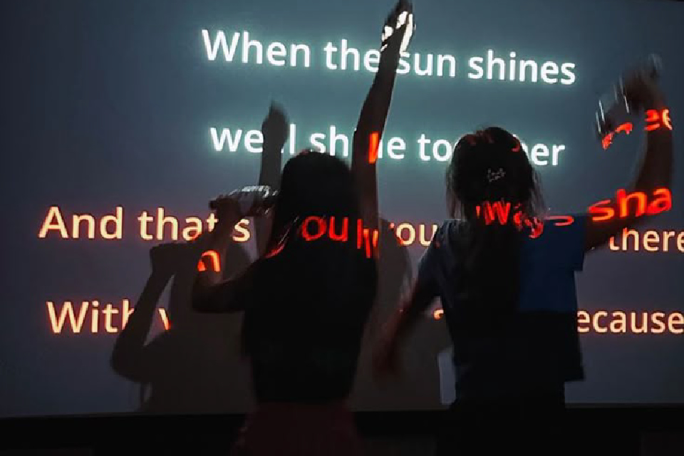 People singing in front of projector