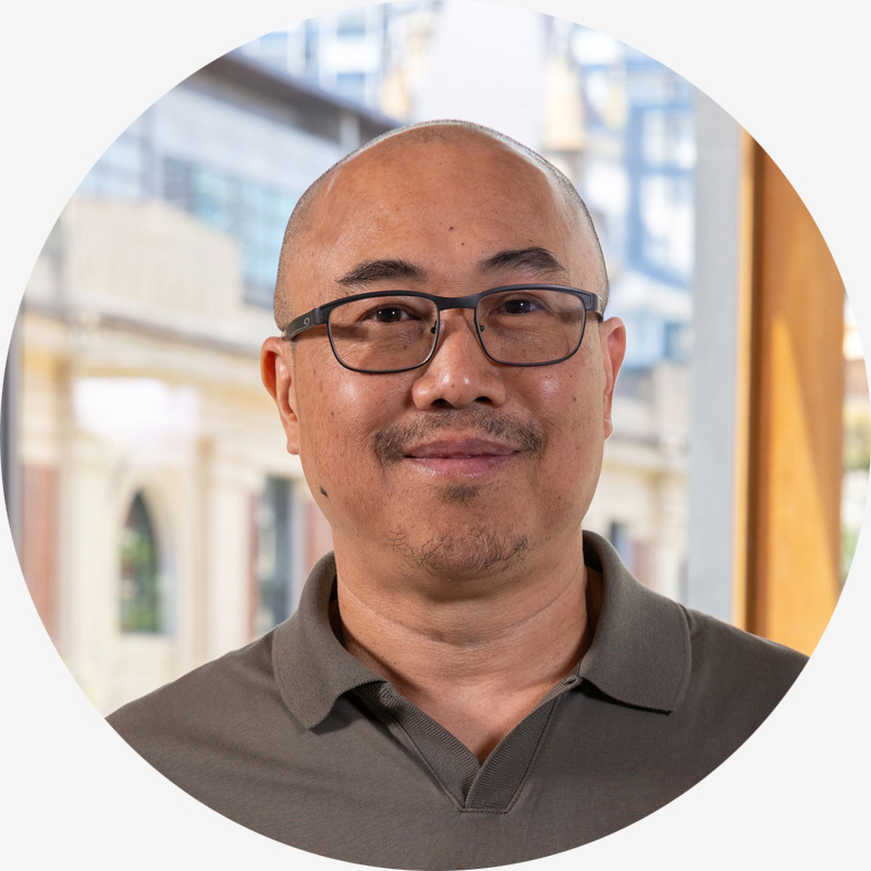 Portrait of Ace Authors, he is bald with glasses and wears a brown shirt.