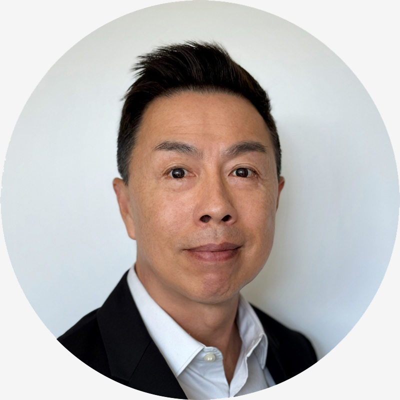 Portrait of Professor Tuck Wah Leong, he has tanned skin, black hair, brown eyes, and is wearing a white button-up shirt with a black suit jacket.