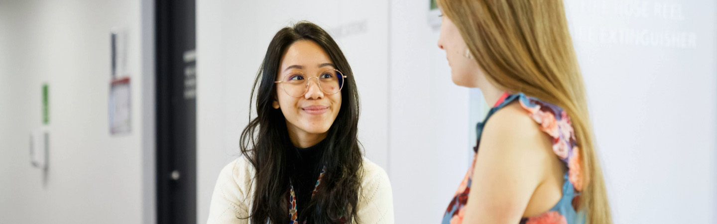 Two women talking in an office setting.
