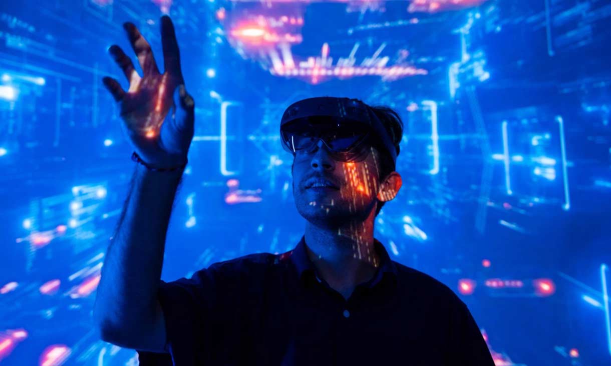 Person standing in front of a digital, futuristic blue background with glowing lights, raising their hand as if interacting with virtual elements.