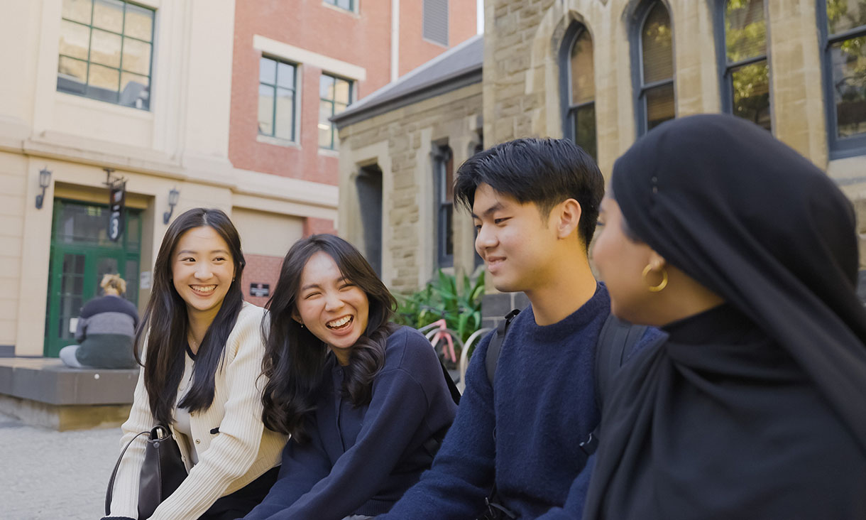 Students sitting together and talking in an outdoor campus courtyard.