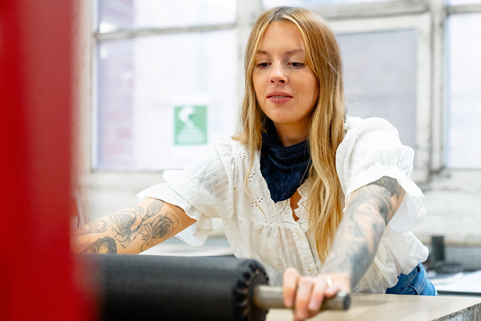 Female student resting arm on desk in studio, surrounded by artwork on walls and desk