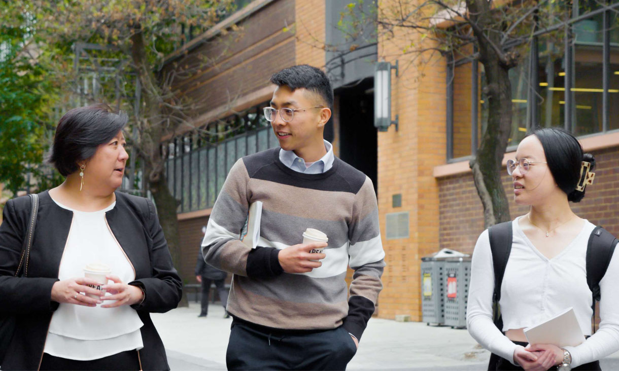 A mentor talks to two students while they walk.