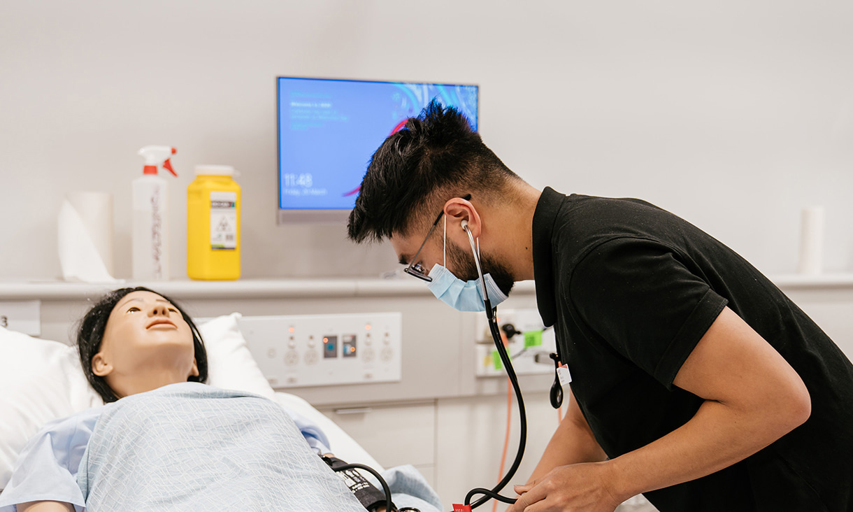 A nursing student practices on a dummy.