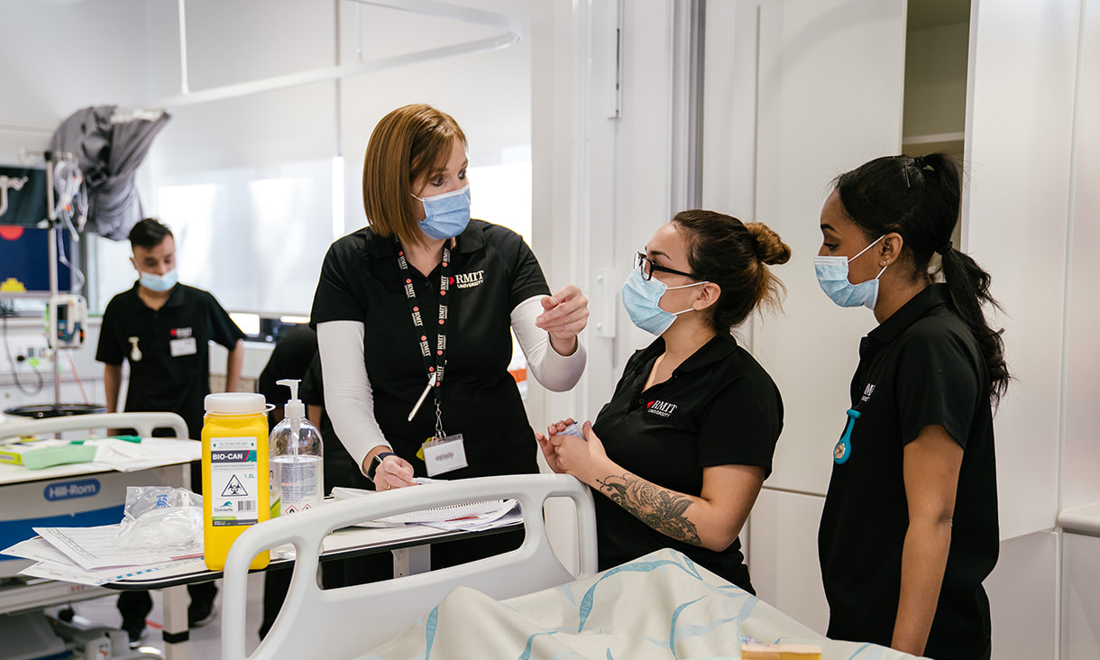 A nurse tutor instructs RMIT nursing students in a clinical setting.