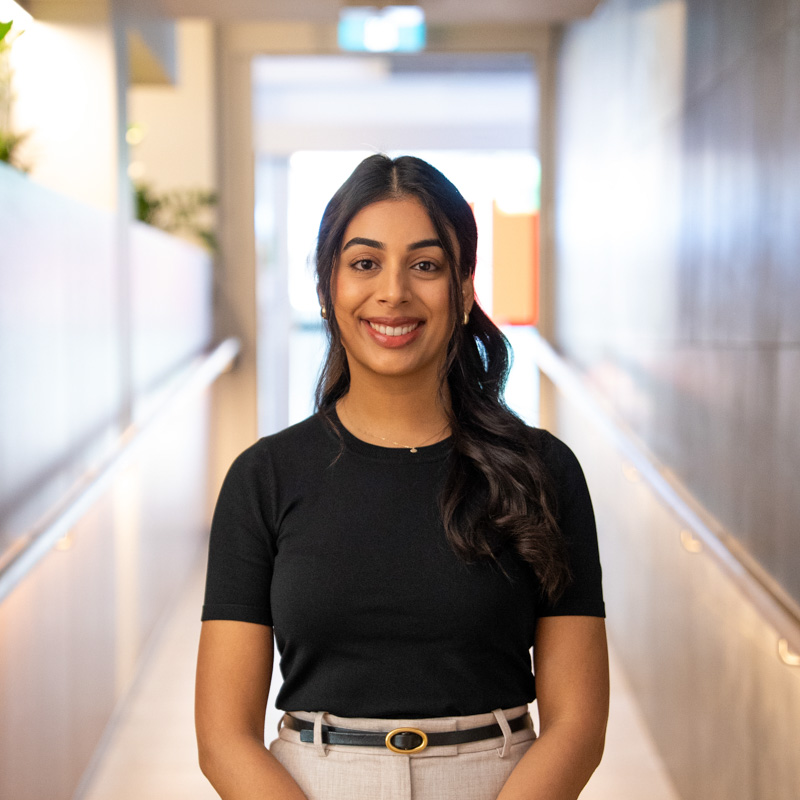 A portrait photograph of Tarika smiling and looking directly at the camera.