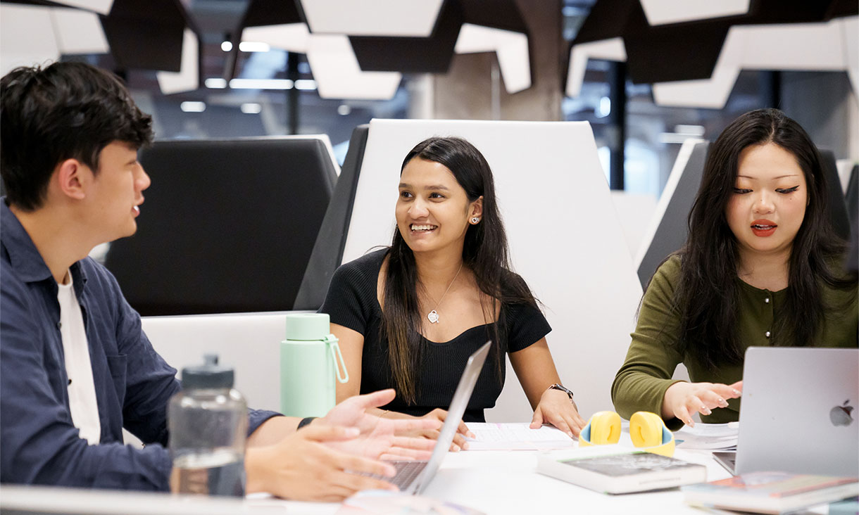 Three international students collaborating in group work.