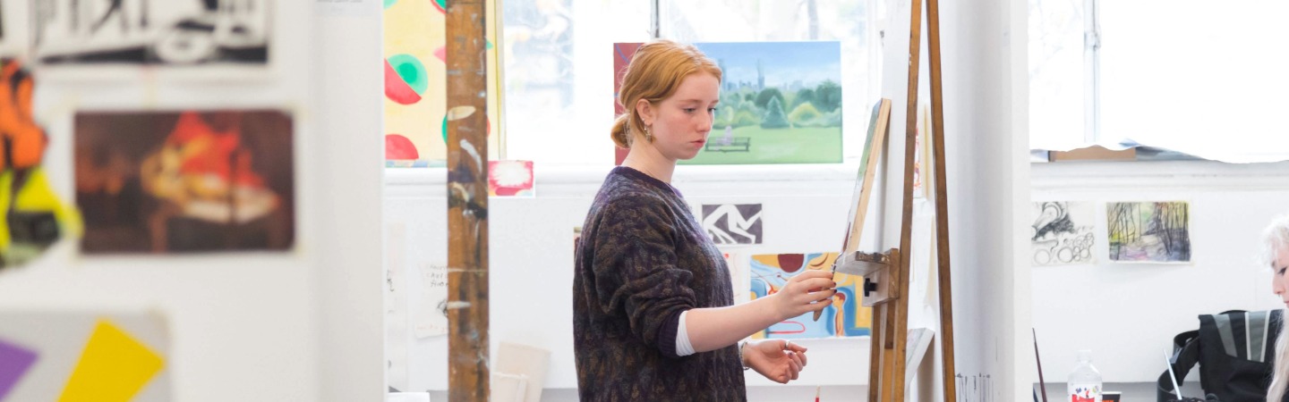 Woman standing painting at an easel. 