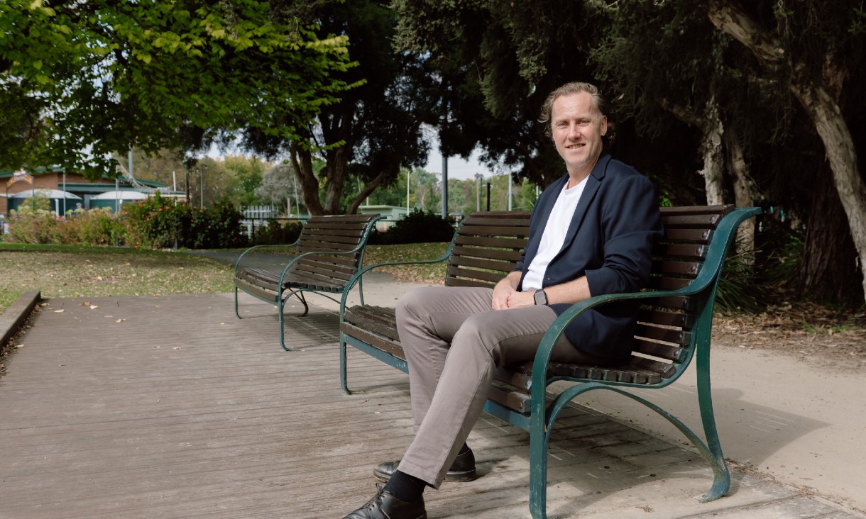 RMIT alumni Dean Worthington sitting on a park bench