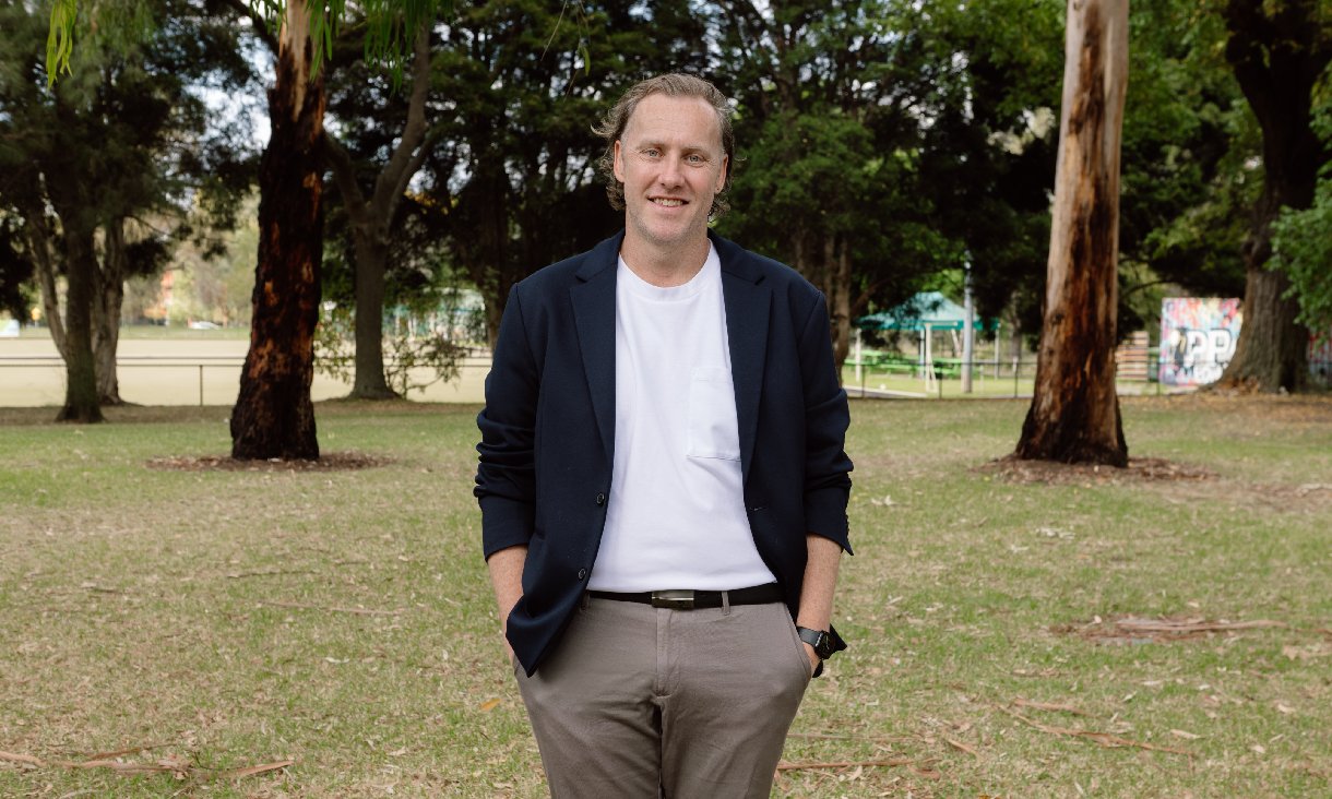 RMIT alumni Dean Worthington standing in a park, looking at the camera