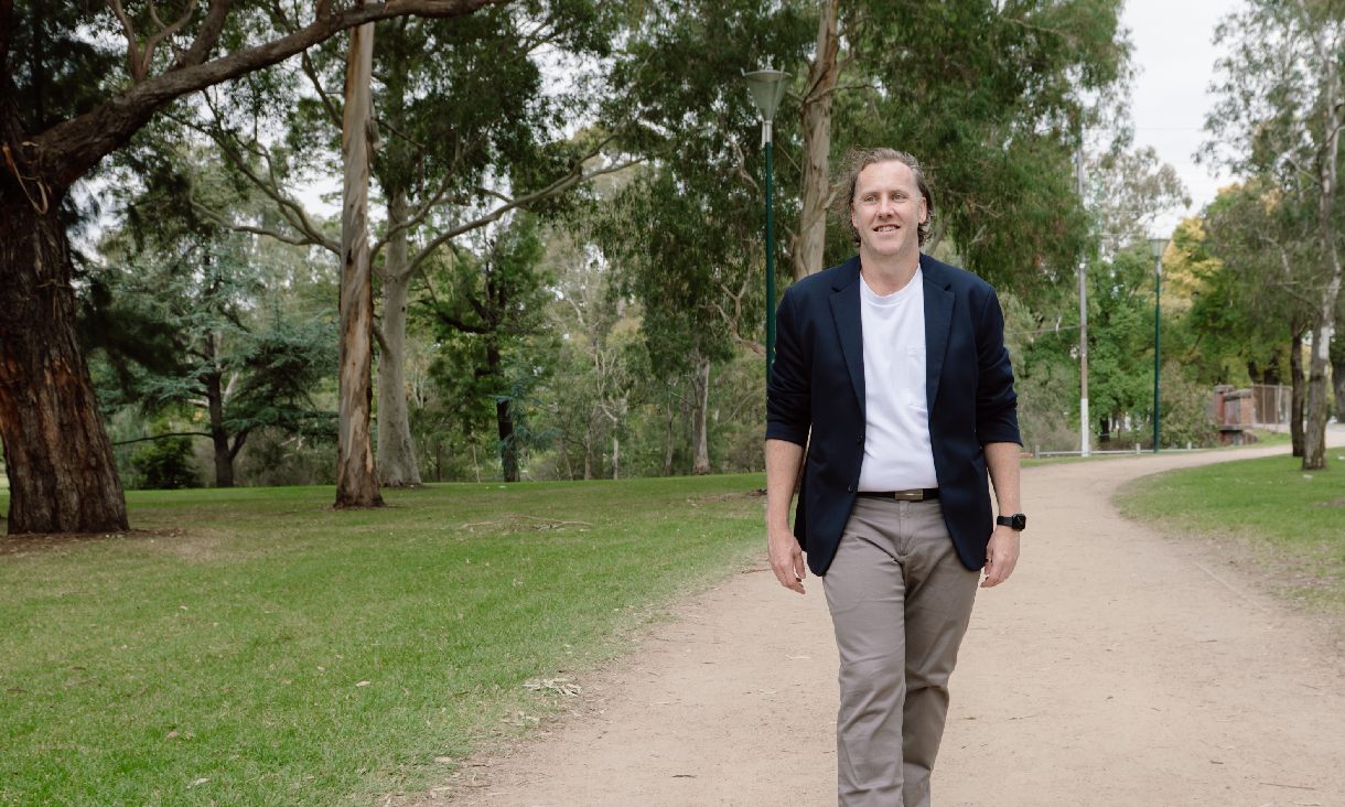 RMIT alumni Dean Worthington walking along a grassy path