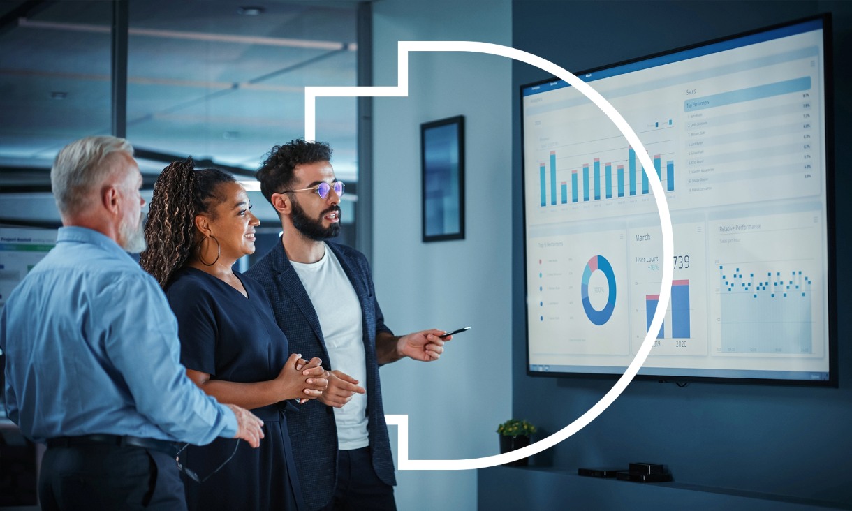 Three colleagues discussing data visualisations on a large screen in an office setting.