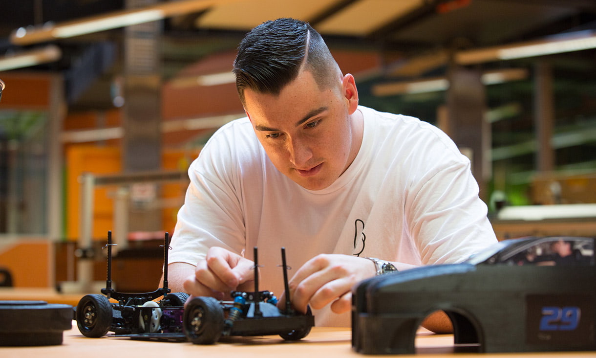 Male engineering student arched over to examine device