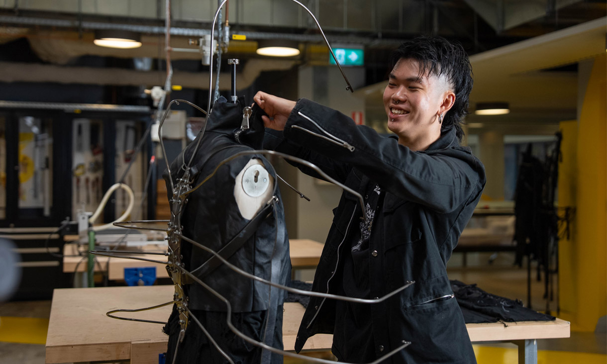 An RMIT fashion student working on a costume made of black fabrics and metal wires