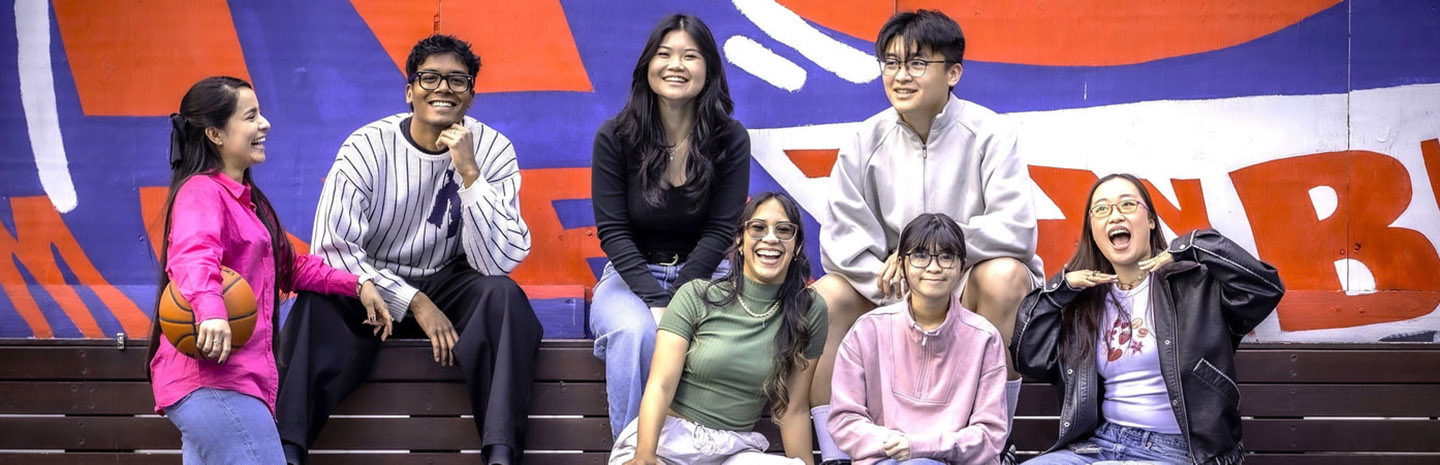 Students smile at the camera while sitting on campus stairs.