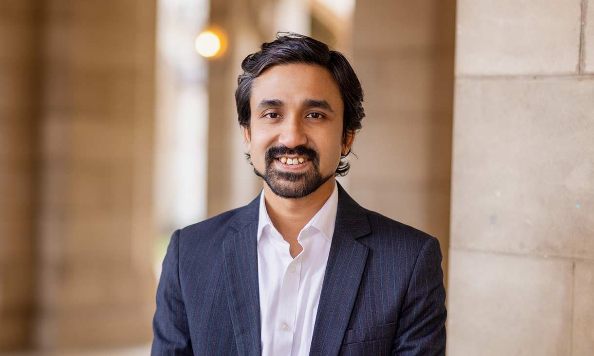 Male student in shirt and suit jacket smiling.