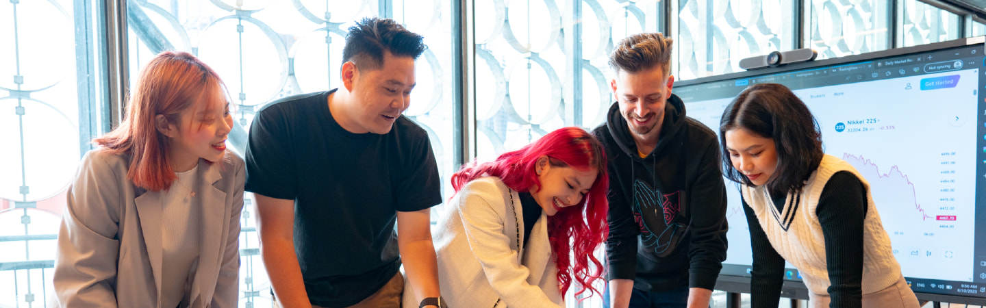 A group of students stadning in fromt of a large screen with graphical data displayed