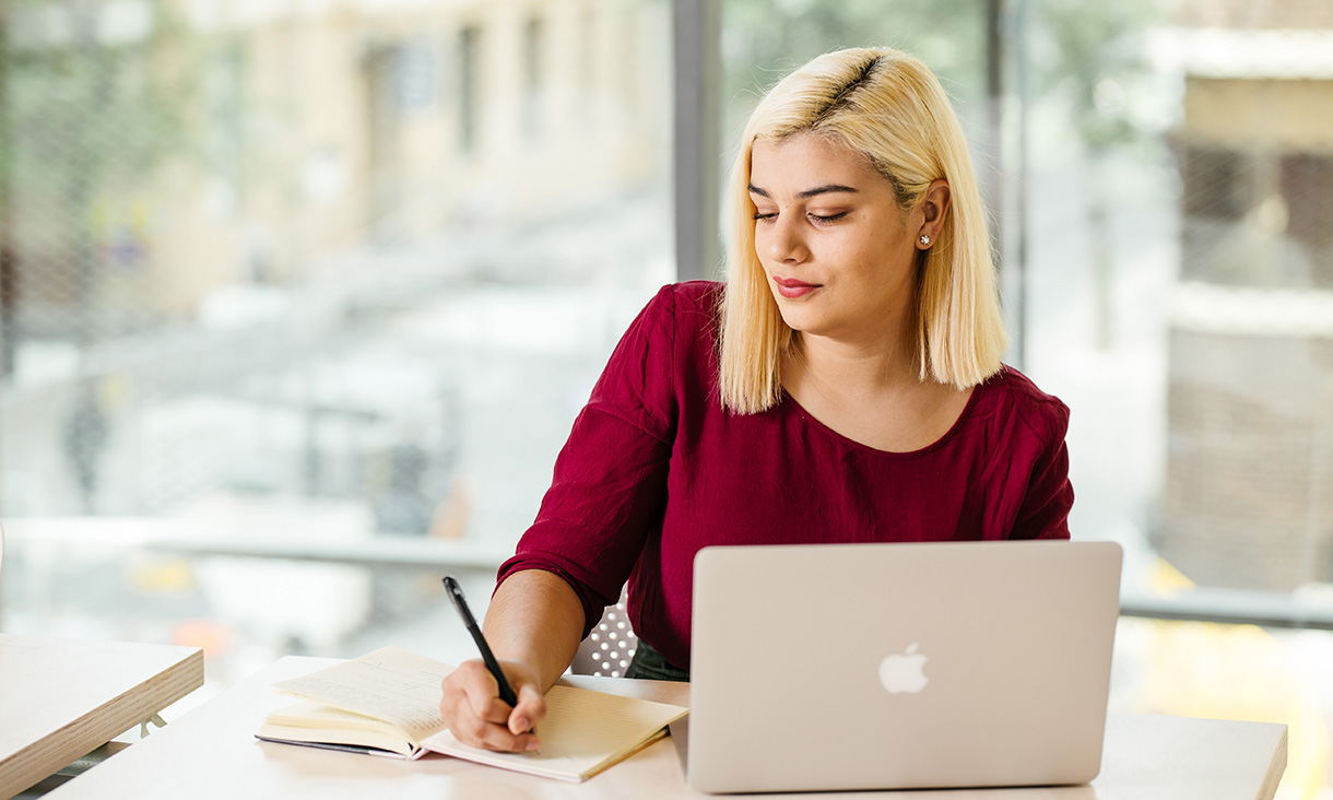 Female student writing down notes in New Academic Streets Garden building