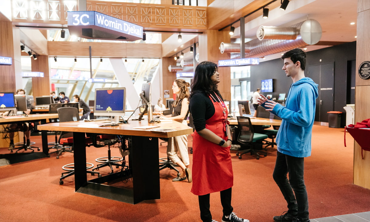 Students talking in front of a desks and computers