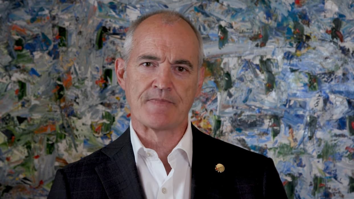 Alec Cameron faces the camera in front of a textured blue and green painting