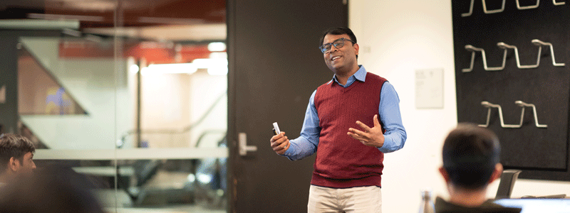 Photograph of man speaking to a classroom with seated students.