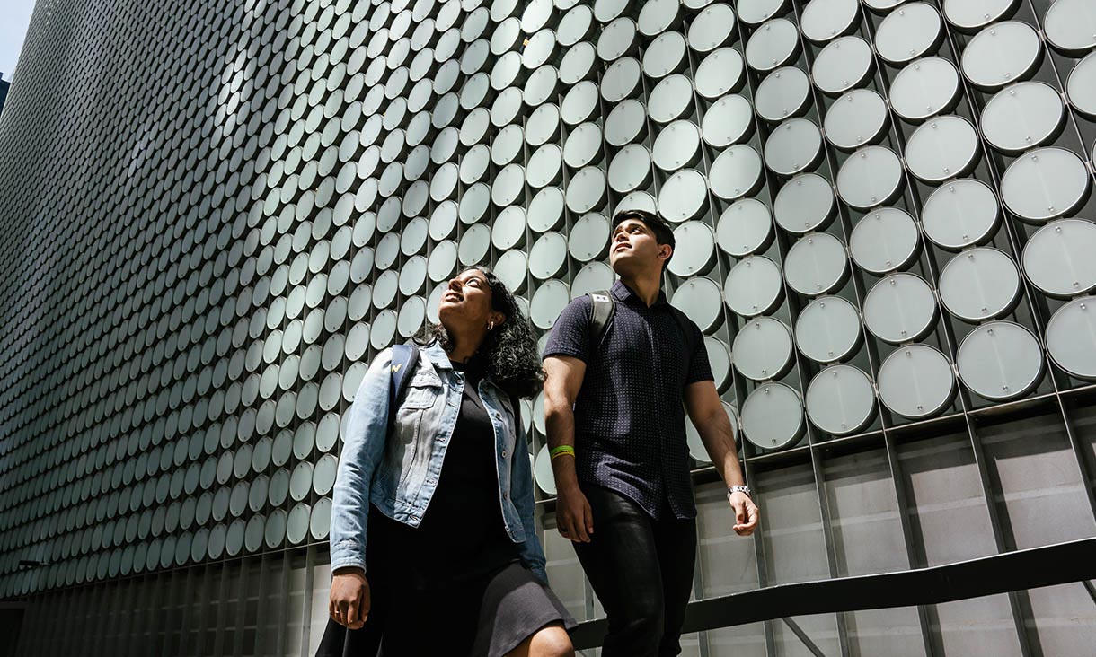 two students walking outside of Building 100