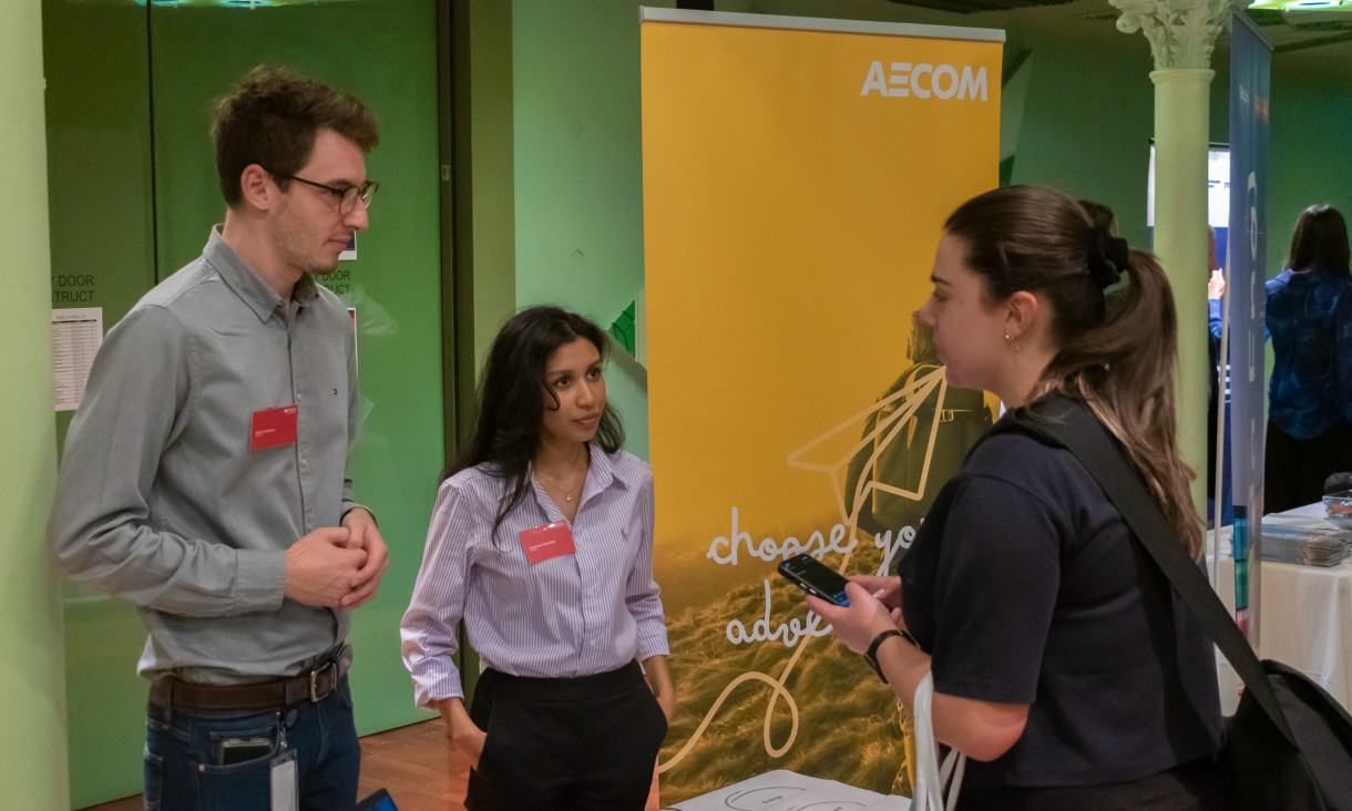 Image of a group of people standing in front of a AECOM sign.