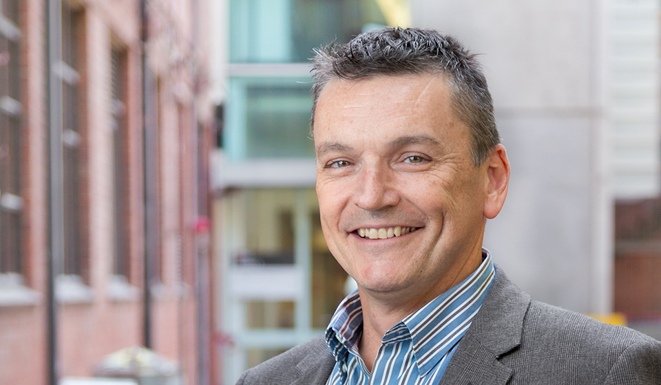 Male student outside RMIT building, smiling, looking towards camera