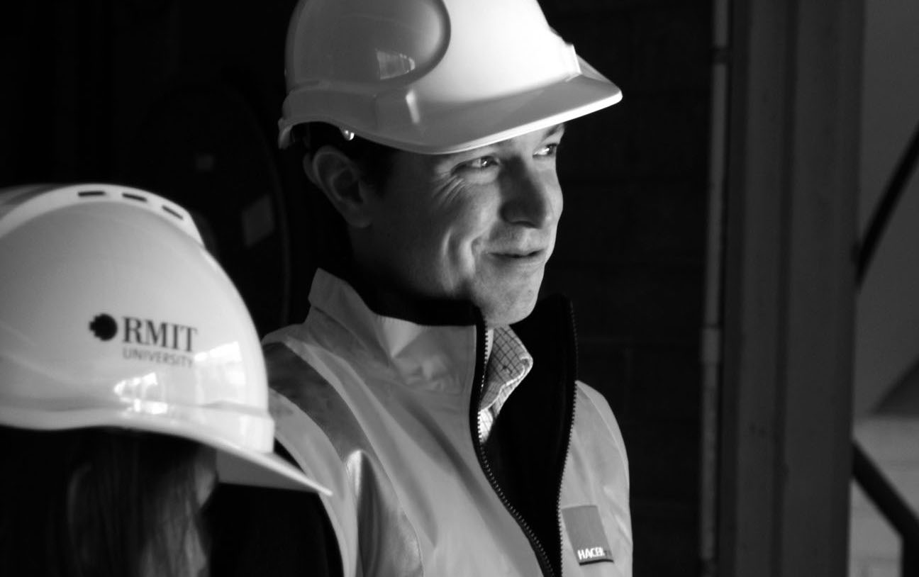 Man wearing a hard hat and construction vest smiling (black and white image)