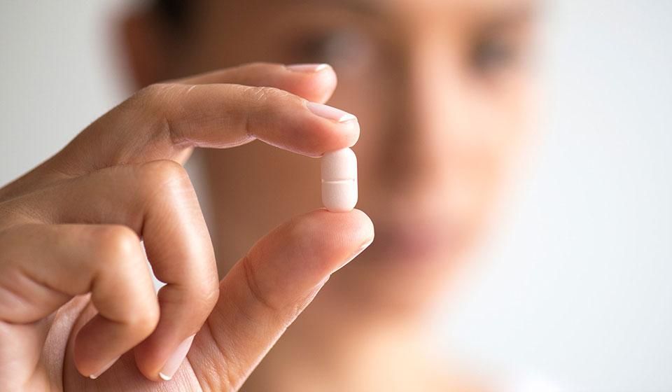 Person holding capsule between fingers.