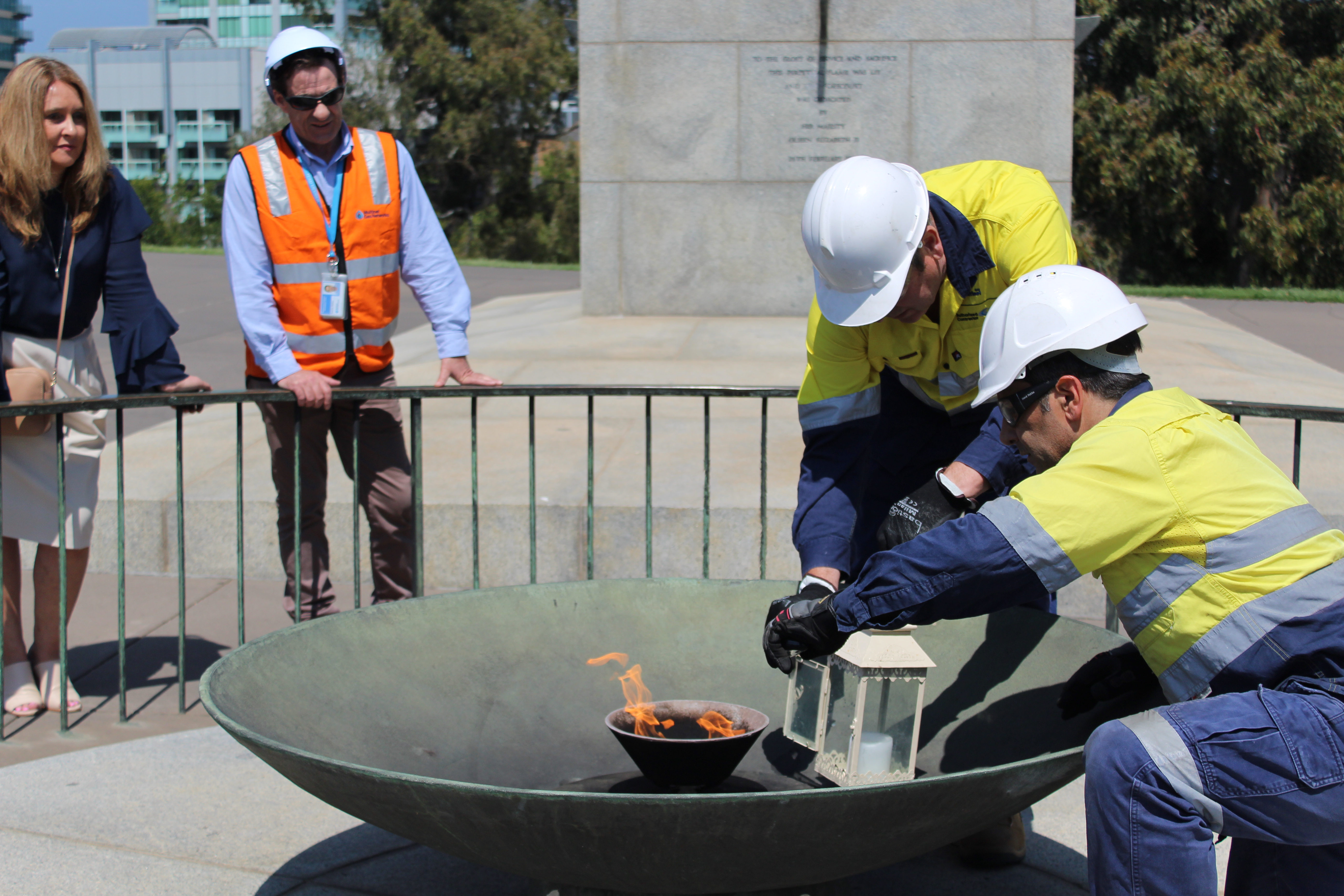Workers keep the flame alive inside a lantern during installation of the new burner.
