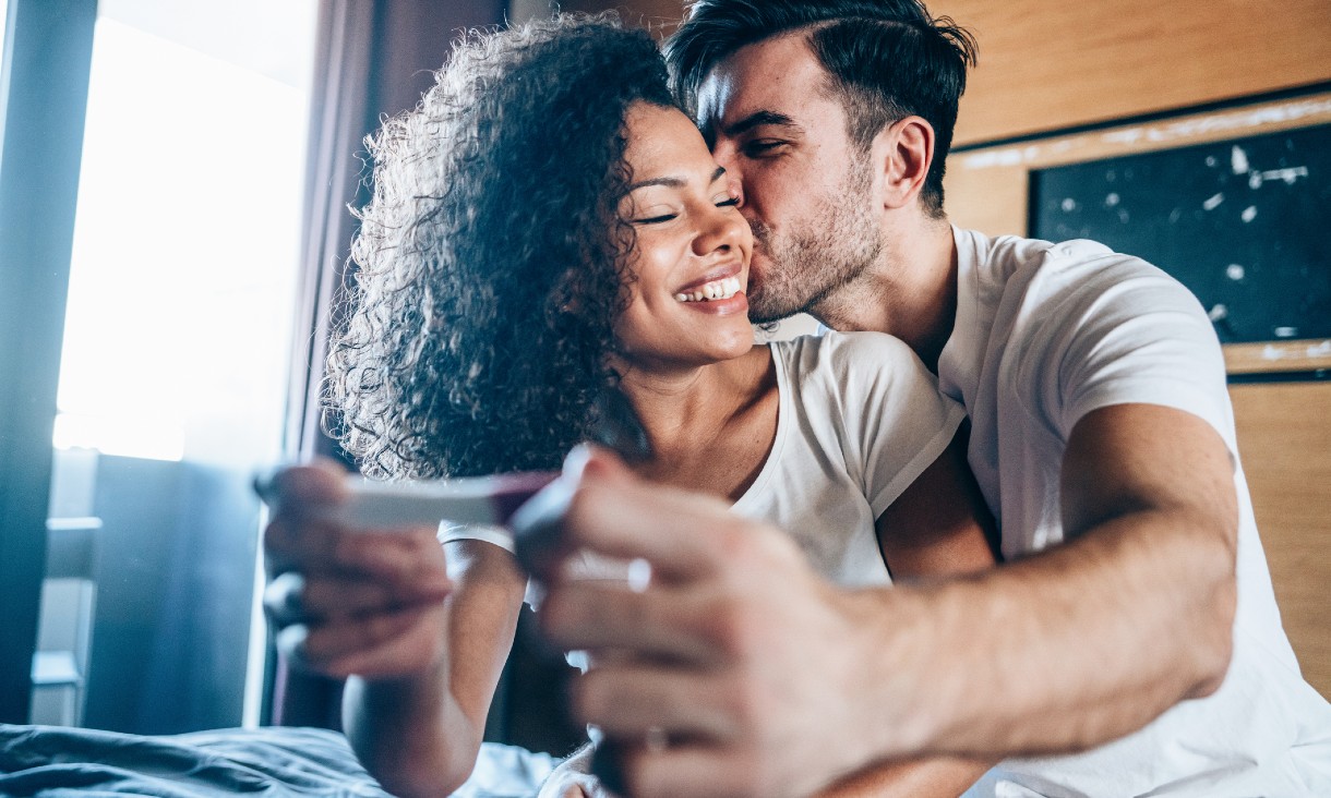 A couple smiling and holding a pregnancy test