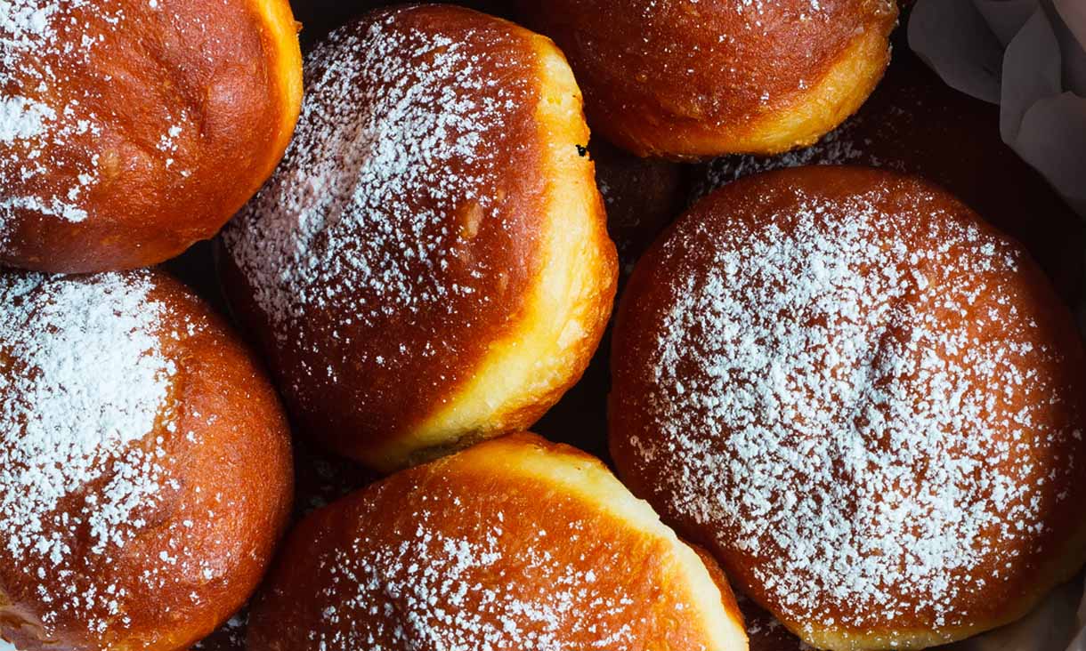 A box of donuts with powdered sugar on top.