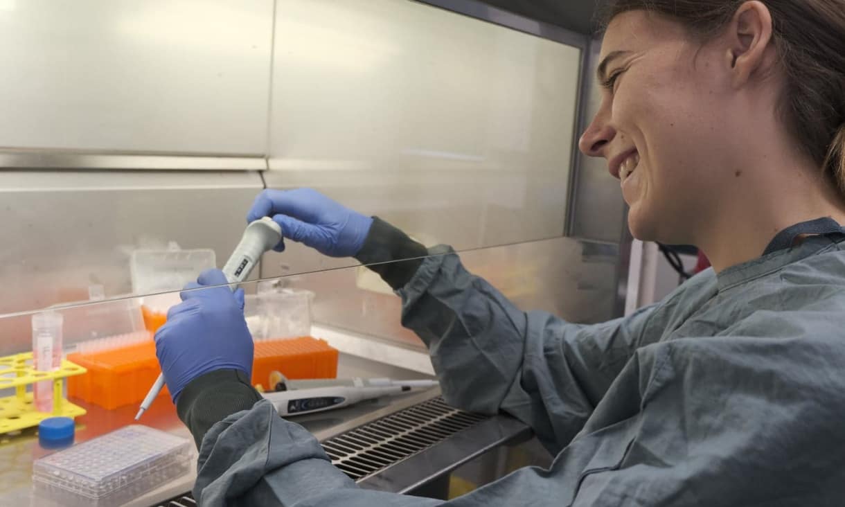 A person inserting liquid into a test tube in a lab