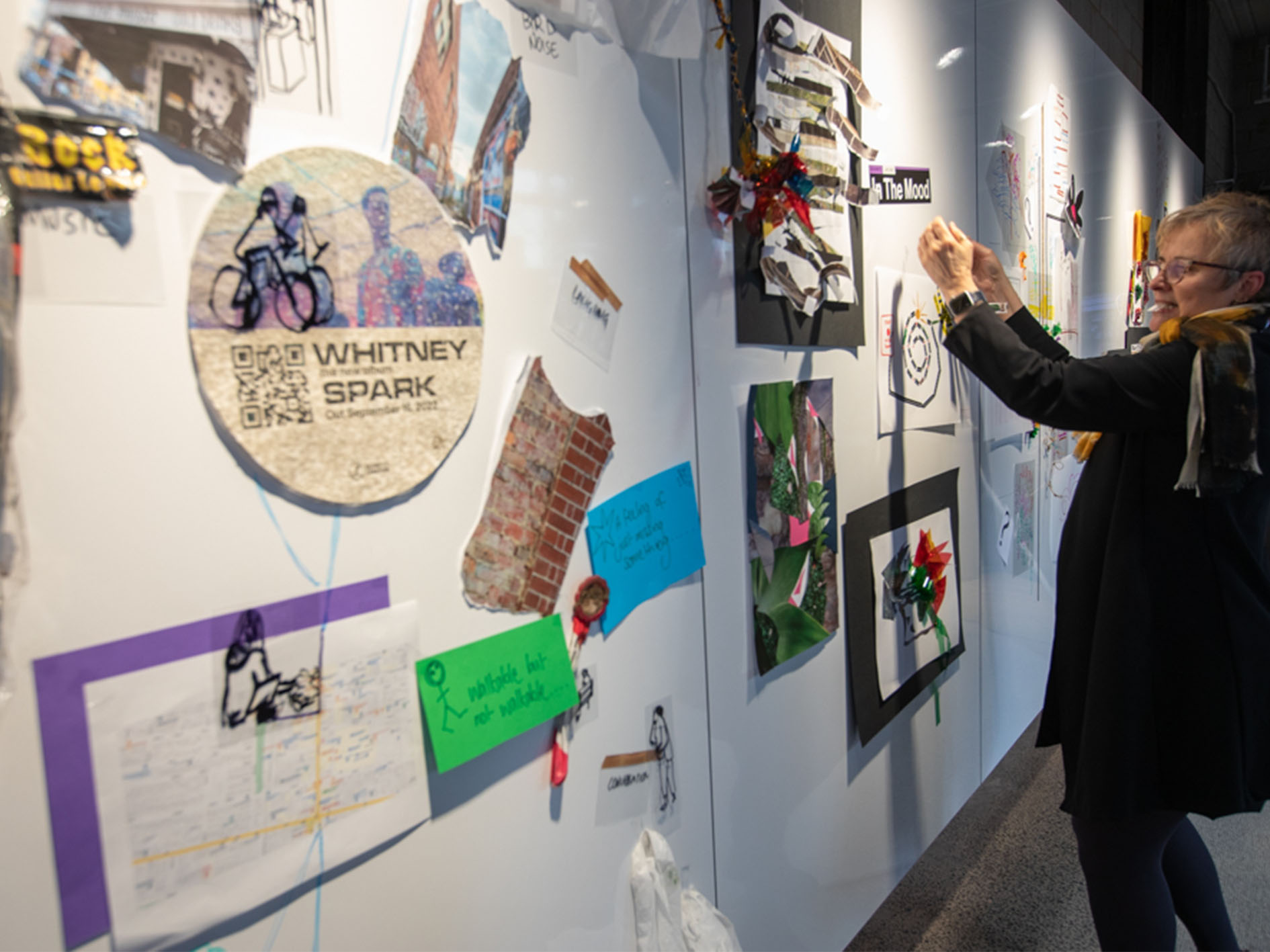 A person pins an idea to a whiteboard covered with paper and writing