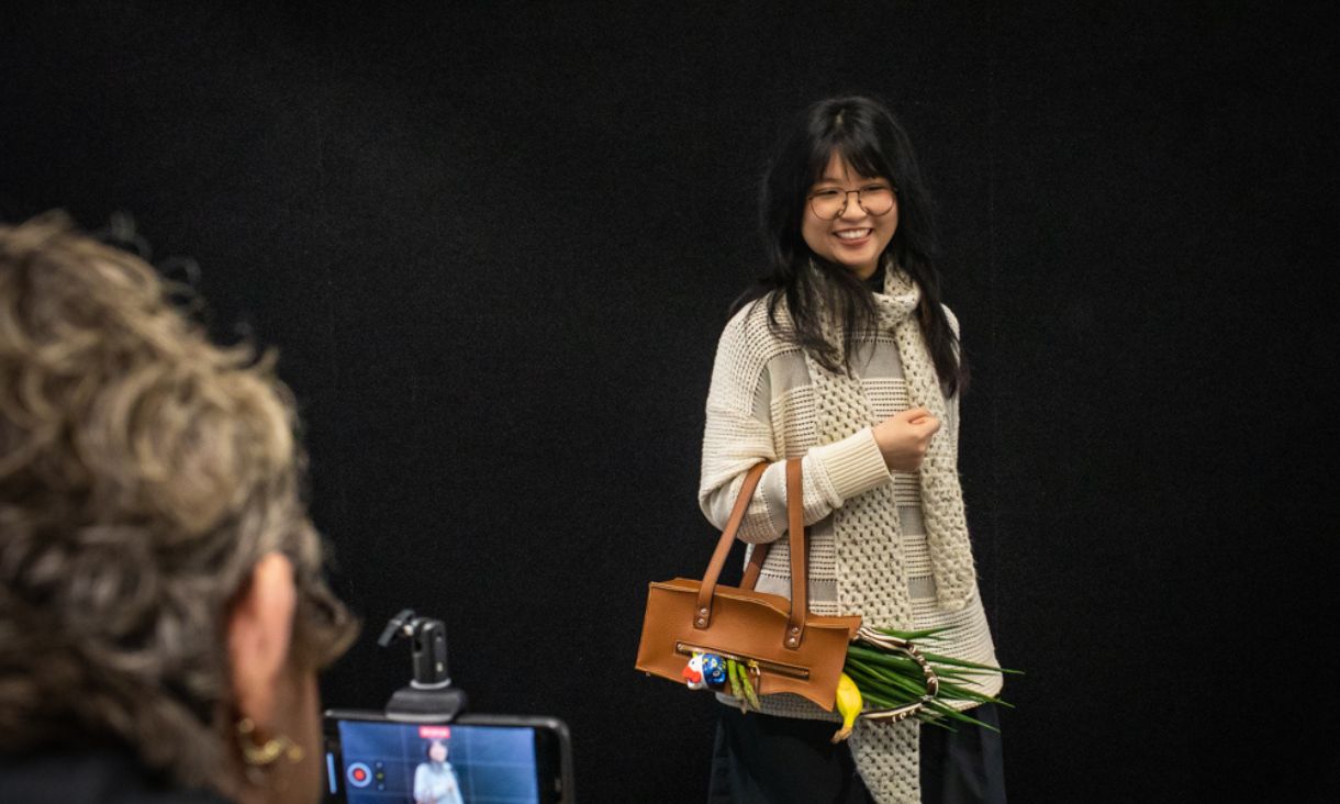 Lady in front of an iPhone holding a leather handbag