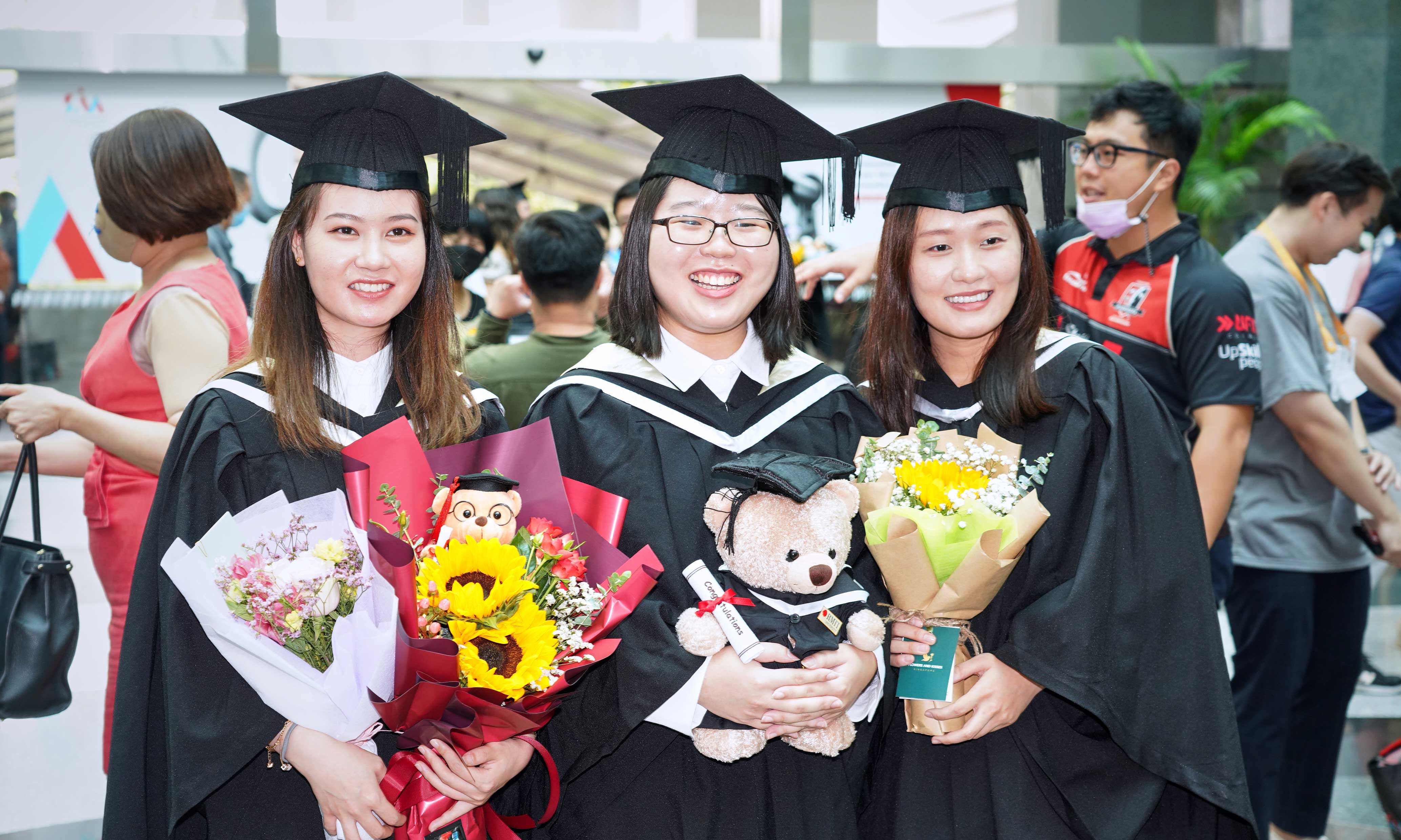 Three female graduates smiling off camera