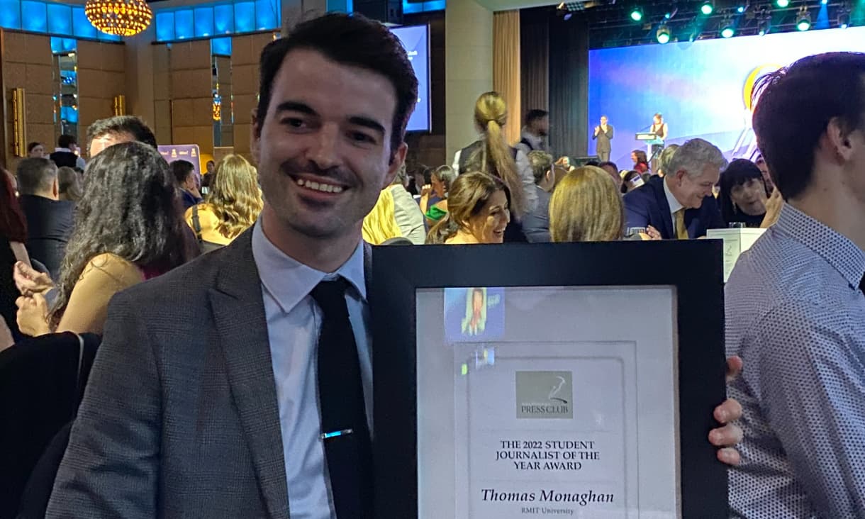 Thomas Monaghan holds up his certificate and smiles