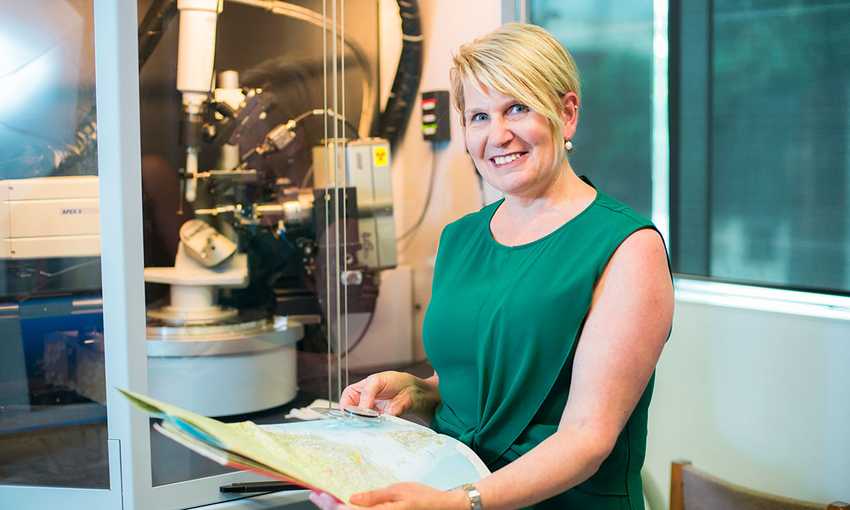 Kay Latham smiling at camera holding a map of Australia