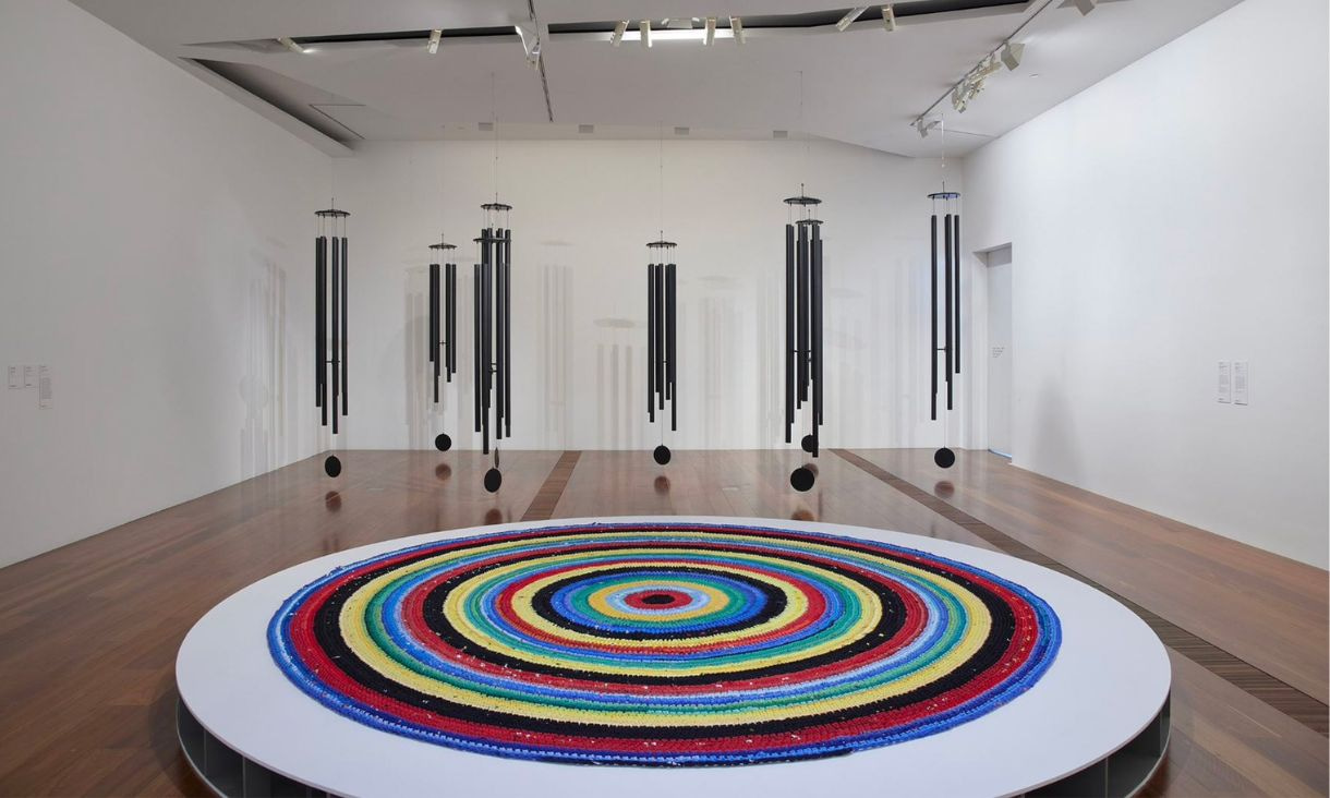 An art installation with a circular structure in the foreground, and black hanging structures in the background