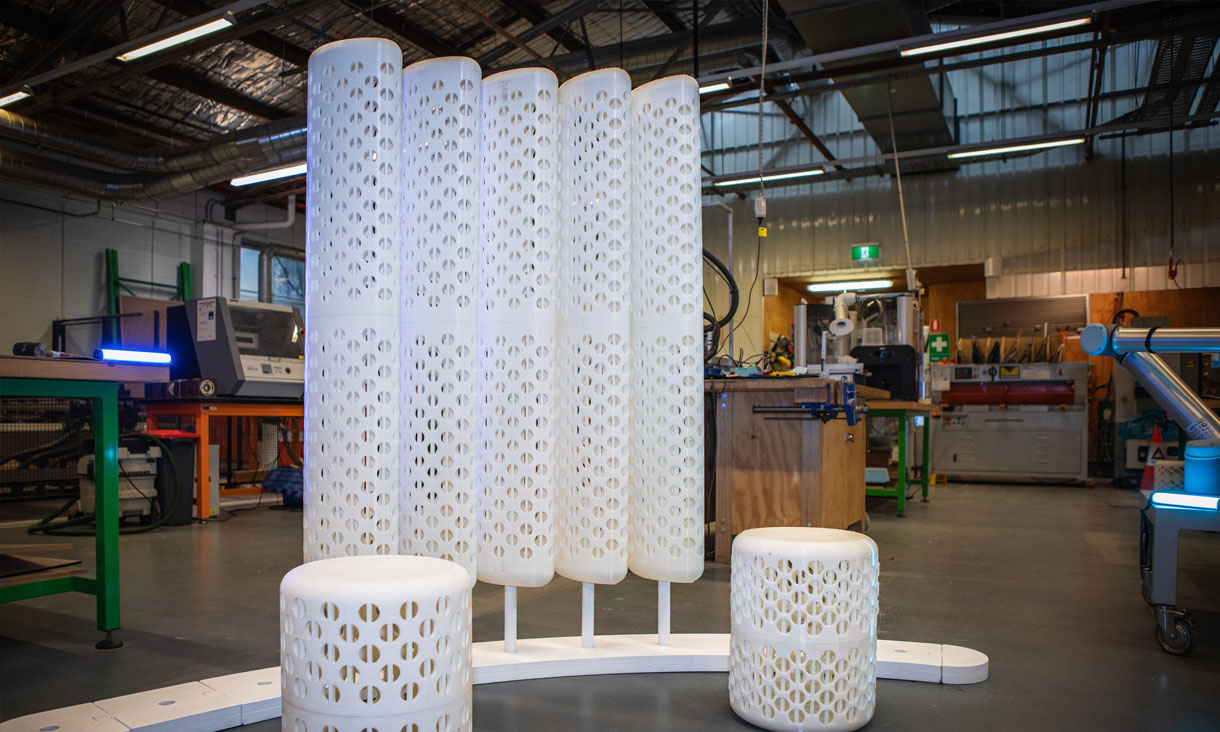 3D printed modular furniture in a workshop, featuring privacy dividers and two stools.