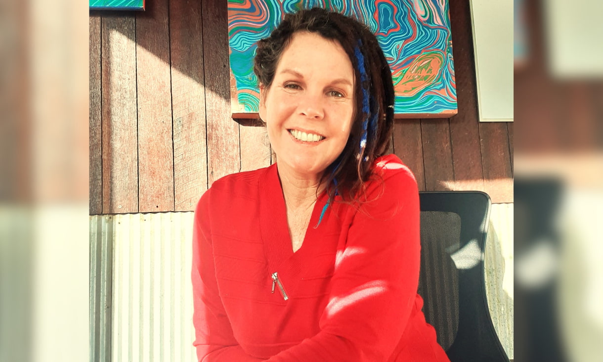 Lady sitting on a chair in front of Aboriginal art