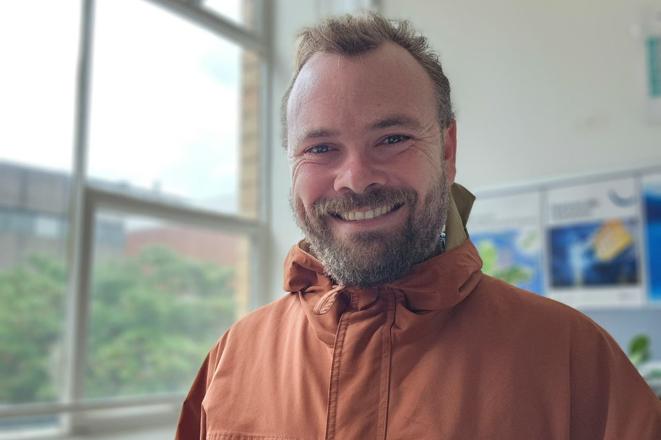 Peter Sherrell stands in a classroom next to a window