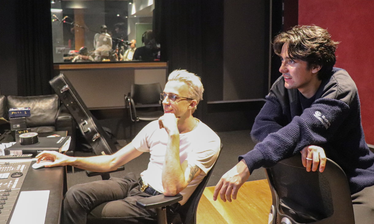2 men sit a recording studio desk