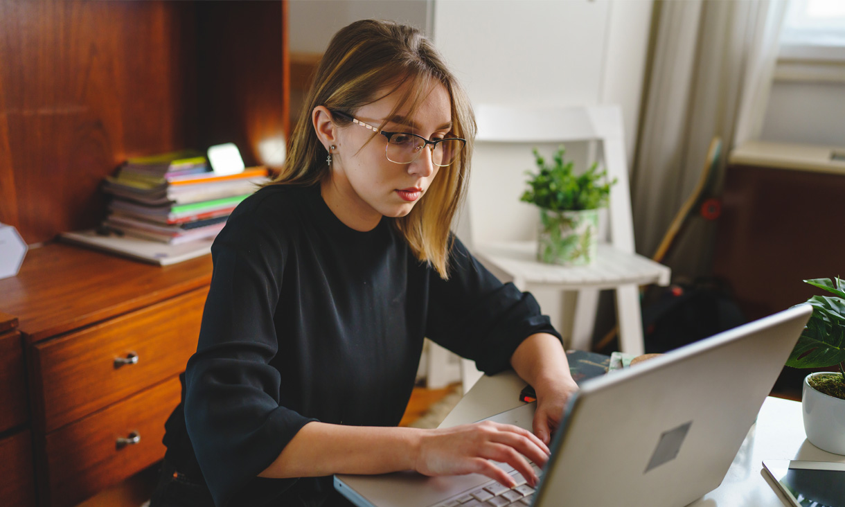 A person is tying something on their laptop in their home.